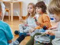 Kinder musizieren mit Holzstäben, Rasseln, einer Trommel und einem Maracas. Welche Instrumente gibt es?