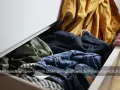 Offener Schubladeninhalt mit Kleidung. Ein Mann greift hinein, um sich für den Physiotherapie-Termin anzuziehen.