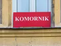 Czerwona tablica z napisem "KOMORNIK" na tle okna. Może to oznaczać zajęcie komornicze wynagrodzenia.