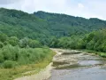Górski potok spiętrza wodę, tworząc malowniczy krajobraz z bujną zielenią lasów i łagodnymi zboczami.