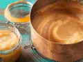 Frisch gekochtes Apfelmus selber machen: Ein Kupfertopf voller Mus neben zwei Gläsern mit dem fertigen Ergebnis.