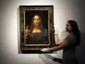 En kvinna med vita handskar hanterar den berömda tavlan "Salvator Mundi", ibland kallad "Mona Lisa tavla" av misstag.