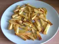 Złociste frytki z piekarnika na talerzu. Zastanawiasz się, ile kcal mają frytki z piekarnika? Oto porcja pysznych, pieczonych ziemniaków.