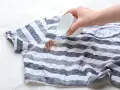Ręka wylewa płyn na paski koszulki, próbując usunąć plamy z czekolady.