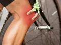 Cyclist holding knee with red pain indicator. Learn about cycling knee pain exercises to get back on the road.