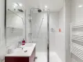 Salle de bain moderne, prête pour la prochaine étape de rénovation. Douche, lavabo et sèche-serviettes blancs.