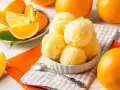 Erfrischendes orangen sorbet in einer Schale, umgeben von frischen Orangen und saftigen Orangenstücken. Ein Löffel liegt bereit.