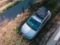 Na dachu samochodu można przewozić bagaż, np. dużą, czarną walizkę zabezpieczoną pomarańczowymi pasami.