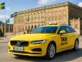 Gelbes Taxi in Schweden vor einem prächtigen Gebäude, mit schwedischen Flaggen im Hintergrund.