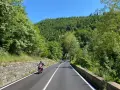 Motociclisti su strade panoramiche in Emilia Romagna, tra colline verdi e cielo azzurro.