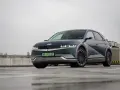 Hyundai Ioniq 5, z charakterystycznymi światłami i felgami, prezentuje swoje imponujące wymiary na mokrym parkingu.