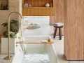 Bain relaxant avec baignoire remplie, robinetterie dorée, plantes et bois. Une belle inspiration salle de bain.