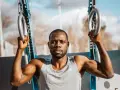 Un homme musclé s'entraîne avec des anneaux de street workout maison.