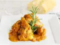Sabroso pollo con almendras en una salsa dorada, adornado con romero fresco. Un plato que invita a disfrutar.