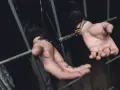 Ręce w kajdankach za kratami, symbolizujące problemy z płaceniem alimentów.