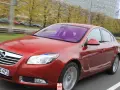 Czerwony Opel Insignia 1.6 Turbo w ruchu ulicznym. Wady tego modelu mogą dotyczyć np. spalania.