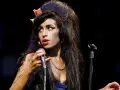 Amy Winehouse z charakterystyczną fryzurą i makijażem, śpiewająca do mikrofonu. Jej styl przypomina legendy z klubu 27, a jej muzyka wciąż żyje w sercach fanów w Polsce.