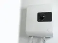 Scaldabagno elettrico istantaneo: pro e contro. Un dispositivo bianco montato a parete con un quadrante nero e indicatori luminosi.