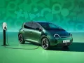 Zielony samochód elektryczny Renault Twingo E-Tech podłączony do ładowarki na tle zielonej grafiki.