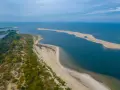 Piękne wybrzeże bałtyckie z piaszczystą mierzeją, zielonymi wydmami i spokojną wodą.