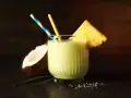Orzeźwiający drink z mlekiem skondensowanym, ananasem i kokosem, ozdobiony słomkami. Idealny na tropikalne popołudnie.