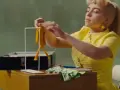 Billie Eilish w żółtej sukience, tworząca coś, co przypomina lalkę, w klimacie "What Was I Made For".