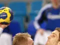 Piłka do piłki ręcznej z napisem "STABIL CHAMP" w dłoni zawodnika. W tle widać innych graczy w niebieskich strojach.