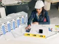 Architektka w kasku analizuje projekt budynku, używając kalkulatora. To może być związane z bms co to jest za system.