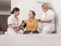 Zwei Pflegekräfte messen einer älteren Frau den Blutdruck. Ein Einblick in die Praxis des Rehabilitationspsychologie Studiums.