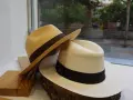 Dos sombreros panameños, uno beige y otro blanco, con cintas oscuras, exhibidos sobre madera y tronco.