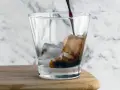 Kall kaffedrink hälls i ett glas med is.