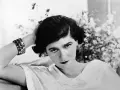 Coco Chanel negli anni '20, con un bracciale scintillante e un'espressione enigmatica.