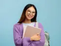 Ragazza con occhiali nuovi per astigmatismo, sorride tenendo libri e zaino.