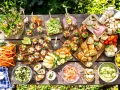 Idée apéro rapide sans cuisson : verrines colorées, crudités, toasts et dips variés sur une table en bois ensoleillée.