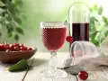 Szklanka z czerwonym winem, wiśnie i butelka. Idealny przepis na wino czerwone z wiśni.