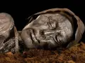 Visage d'une momie des tourbières, le corps préservé dans la tourbe, les traits du visage marqués par le temps.