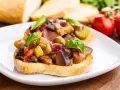 Bruschetta garnie d'un mélange coloré de légumes, évoquant les délices de Capoue.