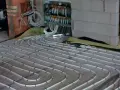 Instalacja ogrzewania podłogowego. Rury ułożone na siatce, podłączone do rozdzielacza. To rozwiązanie obniża koszt ogrzewania.