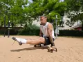 Un homme musclé exécute un exercice de calisthenics, jambes tendues, dans un parc. Un entraînement complet pour un corps athlétique.