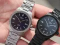 Dwa zegarki Tissot PRC 100 Solar na dłoni. Jeden srebrny z granatową tarczą, drugi czarny z czarną tarczą. Oba posiadają mechanizm solarny.