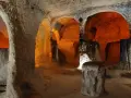 Wnętrze skalnego kościoła w Kapadocji. Pomarańczowe światło oświetla łuki i kolumny wykute w skale, tworząc mistyczną atmosferę tego starożytnego miasta.