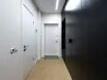 Paredes blancas y negras contrastan en este pasillo largo y estrecho, con puertas y armarios modernos.
