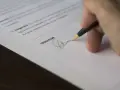 Dłoń podpisuje dokument, być może odpowiedź na pozew wzór.