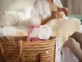 W koszyku widać opakowanie wkładek laktacyjnych Bocioland. W tle kobieta karmi piersią.