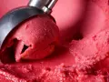Cremiges Erdbeereis selber machen mit Eismaschine: Eine Kugel wird aus dem Behälter gehoben.