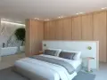 Elegante dormitorio con armarios de madera clara y detalles blancos. La cama, con ropa de cama blanca y cojines grises, se combina perfectamente con la pared de mármol y la bañera.