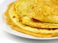 Ein Stapel goldbrauner Eierkuchen auf einem weißen Teller. Perfekt für ein schnelles und einfaches Eierkuchen Rezept.