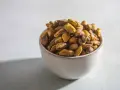 Misternie ułożone pistacje w miseczce. Czy pistacja to orzech? Botanicznie to pestkowiec, ale kulinarnie często traktowany jak orzech.