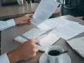 Mężczyzna analizuje dokumenty, szukając informacji o e-sądzie i nakazie zapłaty. Co dalej? Kawa i notatnik czekają.