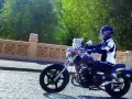 Motocyklista na Kymco Zing 125, zgrabnie pokonujący brukowaną ulicę. Dane techniczne tego modelu pozwalają na komfortową jazdę.